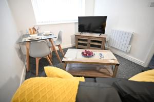 ein Wohnzimmer mit einem TV und einem Couchtisch in der Unterkunft Bubble Rooms in Manchester