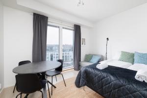 een slaapkamer met een bed, een tafel en een raam bij ULEABO Bright Top Floor Studio in Oulu