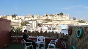 a woman sitting on a balcony with a view of the city at City and Palace view guest House in Udaipur
