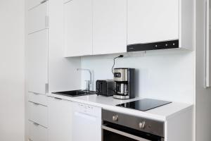 een keuken met witte kasten en een koffiezetapparaat bij ULEABO Bright Top Floor Studio in Oulu