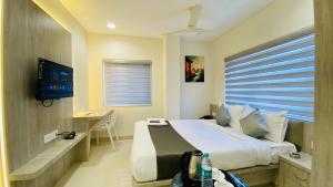 um quarto de hotel com uma cama e uma televisão em Hotel Rex em Indore
