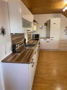 a kitchen with white cabinets and a wooden floor at Ferienwohnung Weberschläger in Ulrichsberg
