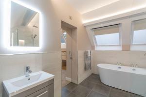 a bathroom with a white tub and a sink at The Old School House - Luxury Themed Apartments in Nottingham