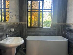 bagno con vasca, lavandino e finestra di Beautiful Cozy Mansion a Kampala