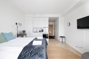 a white bedroom with a large bed and a kitchen at ULEABO Bright Top Floor Studio in Oulu