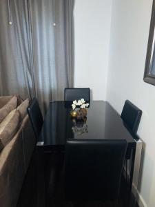 Frobisher Apartment في Erith: طاولة طعام سوداء مع كراسي وأريكة