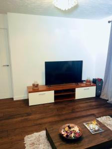 a living room with a flat screen tv on a entertainment center at Frobisher Apartment in Erith
