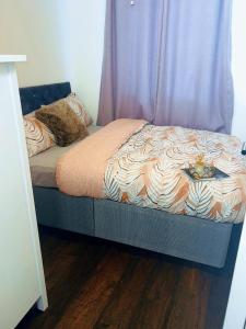 a bed in a bedroom with a curtain and a wooden floor at Frobisher Apartment in Erith