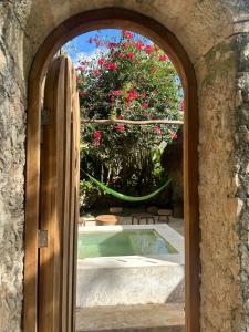uma porta aberta que leva a uma piscina com flores cor-de-rosa em Hacienda Guesthouse with Private Cenote em Espita