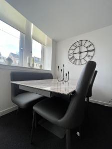 a dining room with a table and chairs and a clock at The M Rooms at 144 in Kirk of Shotts +6 photos