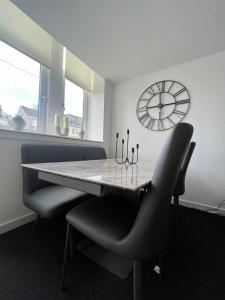 a dining room with a table and chairs and a clock at The M Rooms in Kirk of Shotts