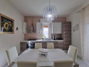a kitchen with a table with chairs and a chandelier at LC e i 7 nani in Pisa