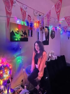 a woman sitting on a chair in a room with lights at orange hostel in Dubai