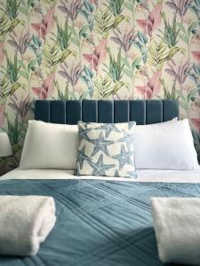 a bedroom with a blue bed with a floral wallpaper at Cosy apartment at the marina in Portishead