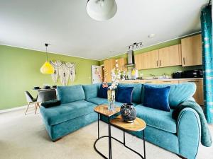 a living room with a blue couch and a kitchen at Cosy apartment at the marina in Portishead