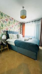 a bedroom with a blue bed with a floral wall at Cosy apartment at the marina in Portishead