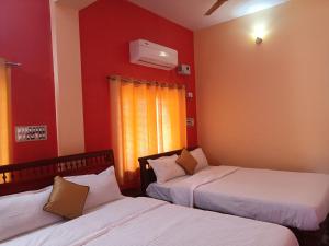 duas camas num quarto com paredes vermelhas em Guru Residency Pondicherry em Pondicherry