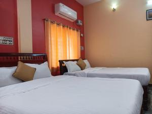 2 camas en una habitación con paredes rojas en Guru Residency Pondicherry, en Pondicherry