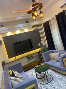 a living room with blue couches and a flat screen tv at Emefa Room in Cotonou