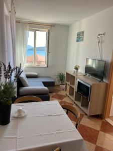 sala de estar con sofá, TV y mesa en Apartments and Rooms Katija & Egon en Korčula