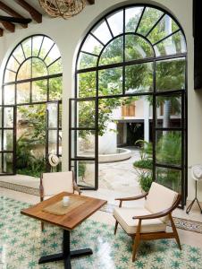 sala de estar con mesa, sillas y ventanas grandes en TreeHouse Boutique Hotel, an adults only boutique hotel en Mérida