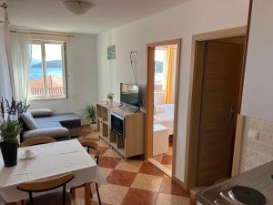 a living room with a couch and a tv and a table at Apartments and Rooms Katija & Egon in Korčula