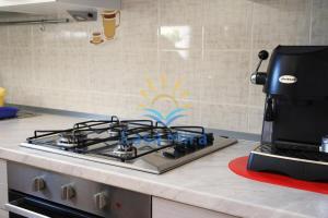 un piano cottura con macchinetta del caffè su un bancone della cucina di Mira Holiday Apartment Chia a Chia