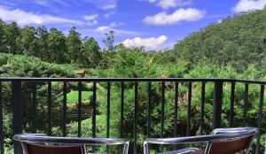 two chairs on a balcony with a view of a garden at The Royal Terrace Holiday Bungalow in Nuwara Eliya