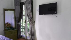 a room with a tv and a window with curtains at The Royal Terrace Holiday Bungalow in Nuwara Eliya