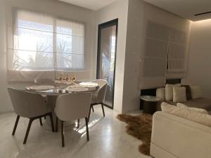 a living room with a table and chairs and a couch at Appartement Californien in Sidi Daoud