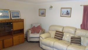 ein Wohnzimmer mit einem Sofa und einem Stuhl in der Unterkunft Come along and enjoy the beautiful Moray Coast in Buckie