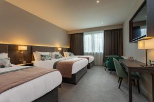 a hotel room with two beds and a desk at McWilliam Park Hotel in Claremorris