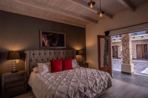 ein Schlafzimmer mit einem Bett mit zwei roten Kissen in der Unterkunft Hotel Boutique Rancho San Jorge in Bernal