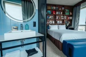 a bedroom with a bed and a sink and a mirror at JOST Hôtel Lille Centre in Lille