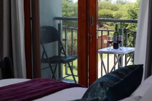 a bedroom with a balcony with a chair and a table with wine glasses at Spacious and luxury 3 bedroom apartment in Midrand