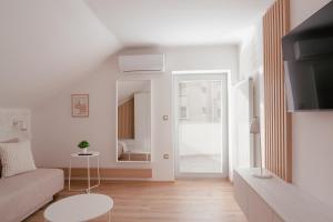 ein weißes Wohnzimmer mit einem Sofa und einem Spiegel in der Unterkunft Luxury 2 bedroom NEW apartment with private parking in Ljubljana