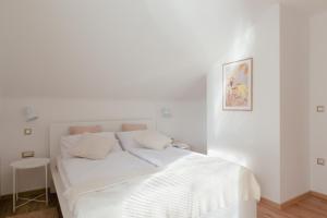 um quarto branco com uma cama branca e um banco em Luxury 2 bedroom NEW apartment with private parking em Ljubljana