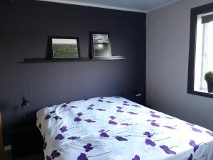 Un dormitorio con una cama con flores púrpuras. en Feriehus ved Barentshavet - Holiday home by the Barents Sea, en Ytre Kiberg
