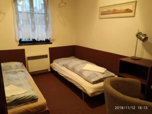 een kleine kamer met 2 bedden en een stoel bij chata Alice in Rokytnice nad Jizerou