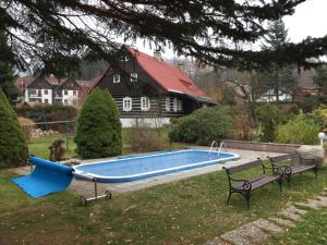 a swimming pool in a yard with a bench and a house at chata Alice in Rokytnice nad Jizerou