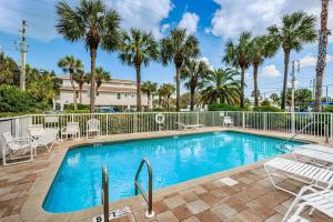 a swimming pool with chairs and palm trees at White Dunes Condo in Clearwater Beach