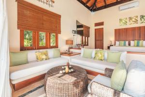 una sala de estar con sofás blancos y una mesa. en Newly added Tropical Bungalow at Green Village, en Punta Cana