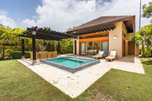 a backyard with a swimming pool and a house at Newly added Tropical Bungalow at Green Village in Punta Cana