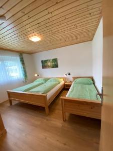 2 bedden in een slaapkamer met een houten plafond bij Ferienwohnung am See in Sankt Kanzian