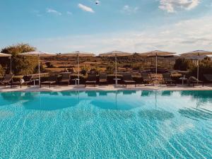 a large swimming pool with chairs and umbrellas at Dimora delle Balze in Noto
