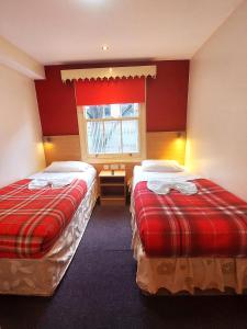 twee bedden in een kamer met rode muren en een raam bij Carlton Hotel in Londen