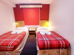 two beds in a hotel room with red walls at Carlton Hotel in London