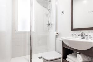 La salle de bains blanche est pourvue d'un lavabo et d'une douche. dans l'établissement BNBHolder Tropical CENTRE, à Madrid