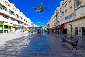 a city street with a palm tree and a bench at Torremolinos. Plaza de Andalucía Apartment in Torremolinos