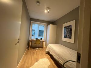 a bedroom with a bed and a desk and a window at New apartment in Hagastaden in Stockholm